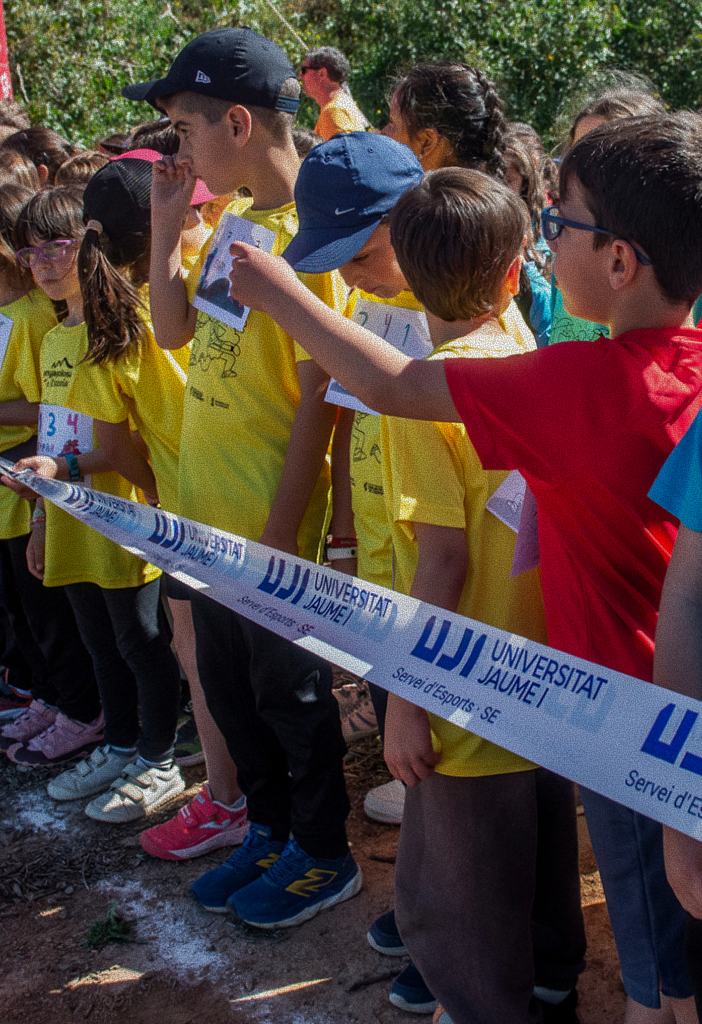Escolares con camisetas de colores junto a la cinta de una actividad deportiva