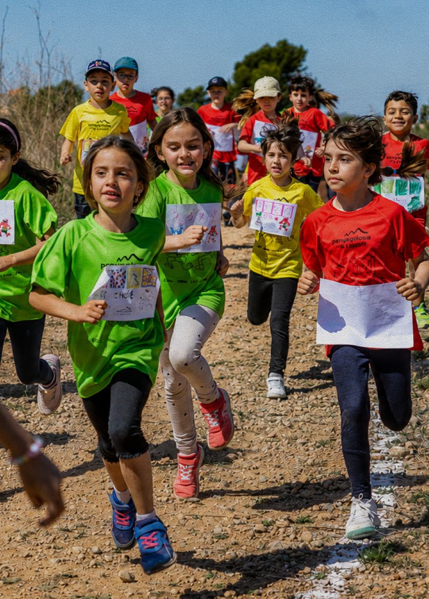 Niñas y niños corriendo por un sendero durante una actividad escolar